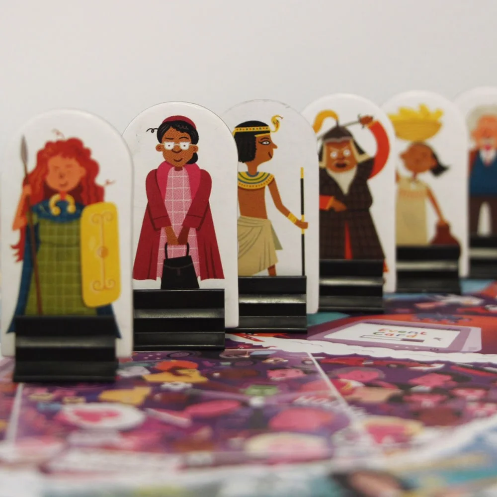 Toy figurines stand upright in a row on a colorful game board. Each figure is depicted in distinct outfits, suggesting different characters or roles within a tabletop game context.